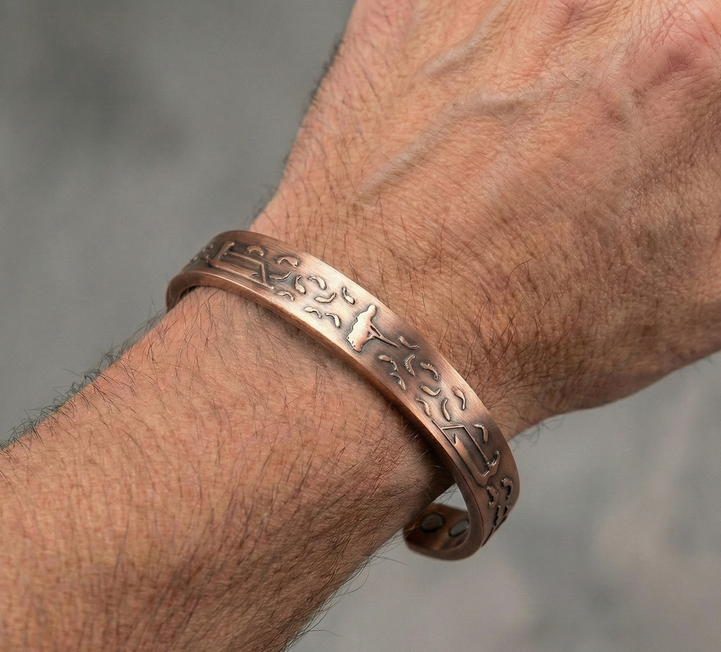 Copper bracelet with intricate designs on a wrist against a neutral background